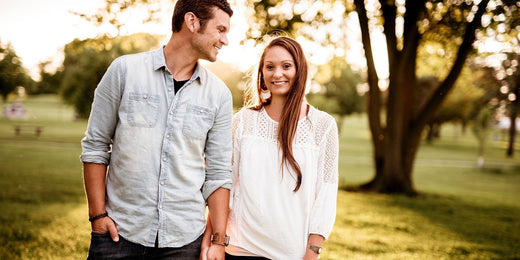 man and woman walking through field holding hands