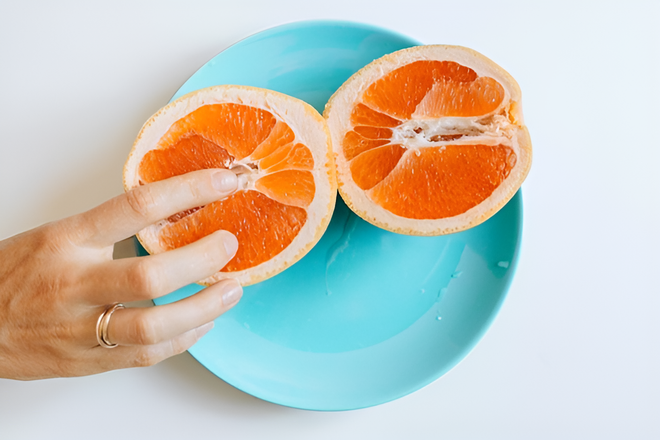 finger in middle of sliced orange.